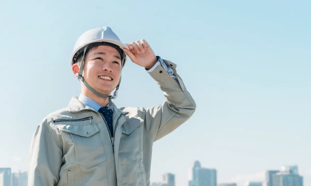 青空の下で現場を見渡す施工管理者